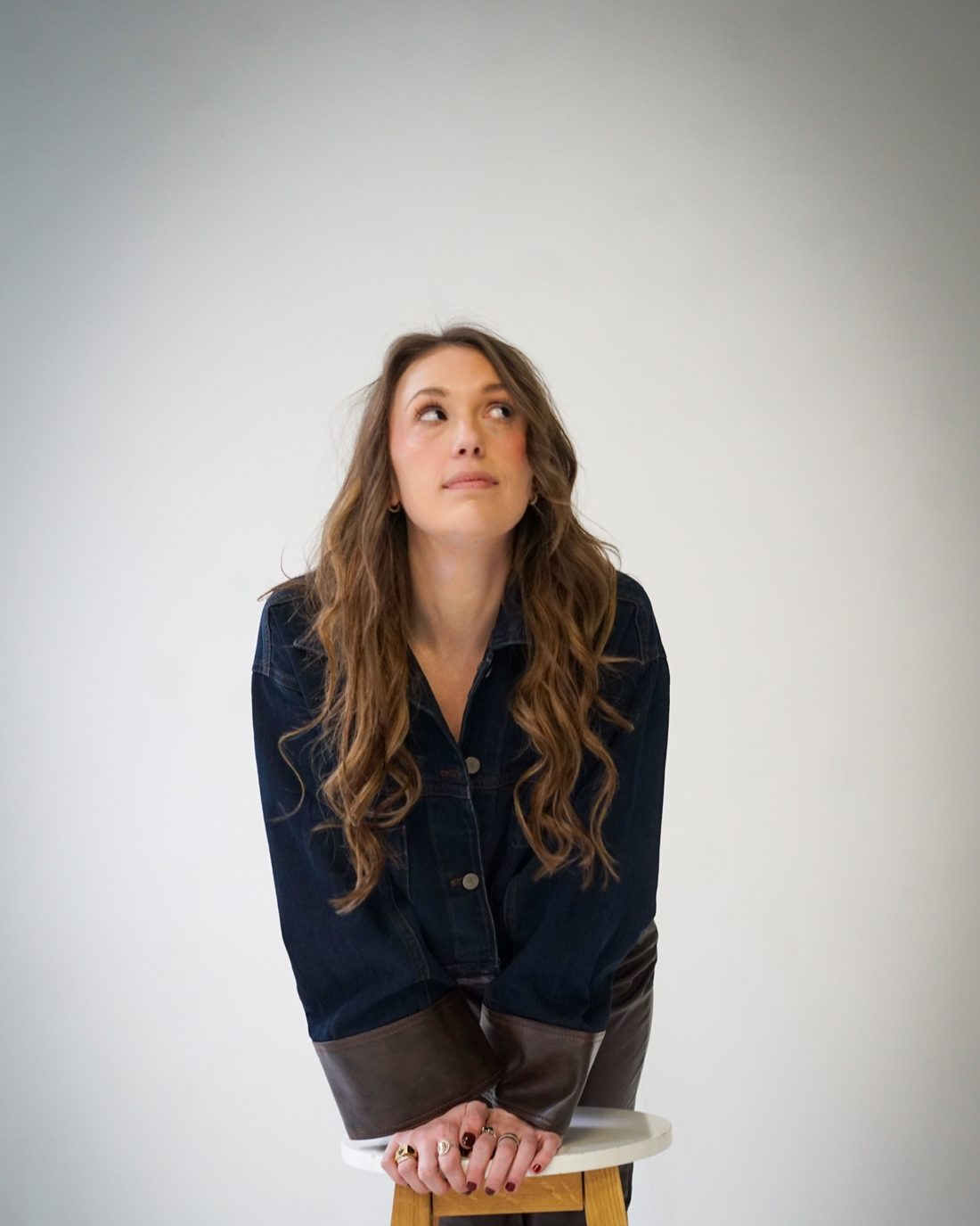 Alise McCreary looking up, hands folded on a stool